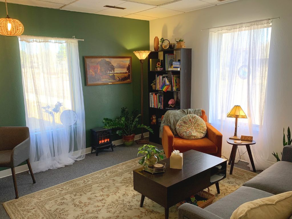 Office space for thereapy with green walls, cream rub, a wooden coffee table, and an orange chair